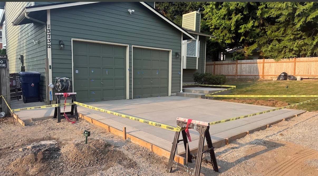 New concrete driveway in front of a two-car garage, with control joints and forms still in place