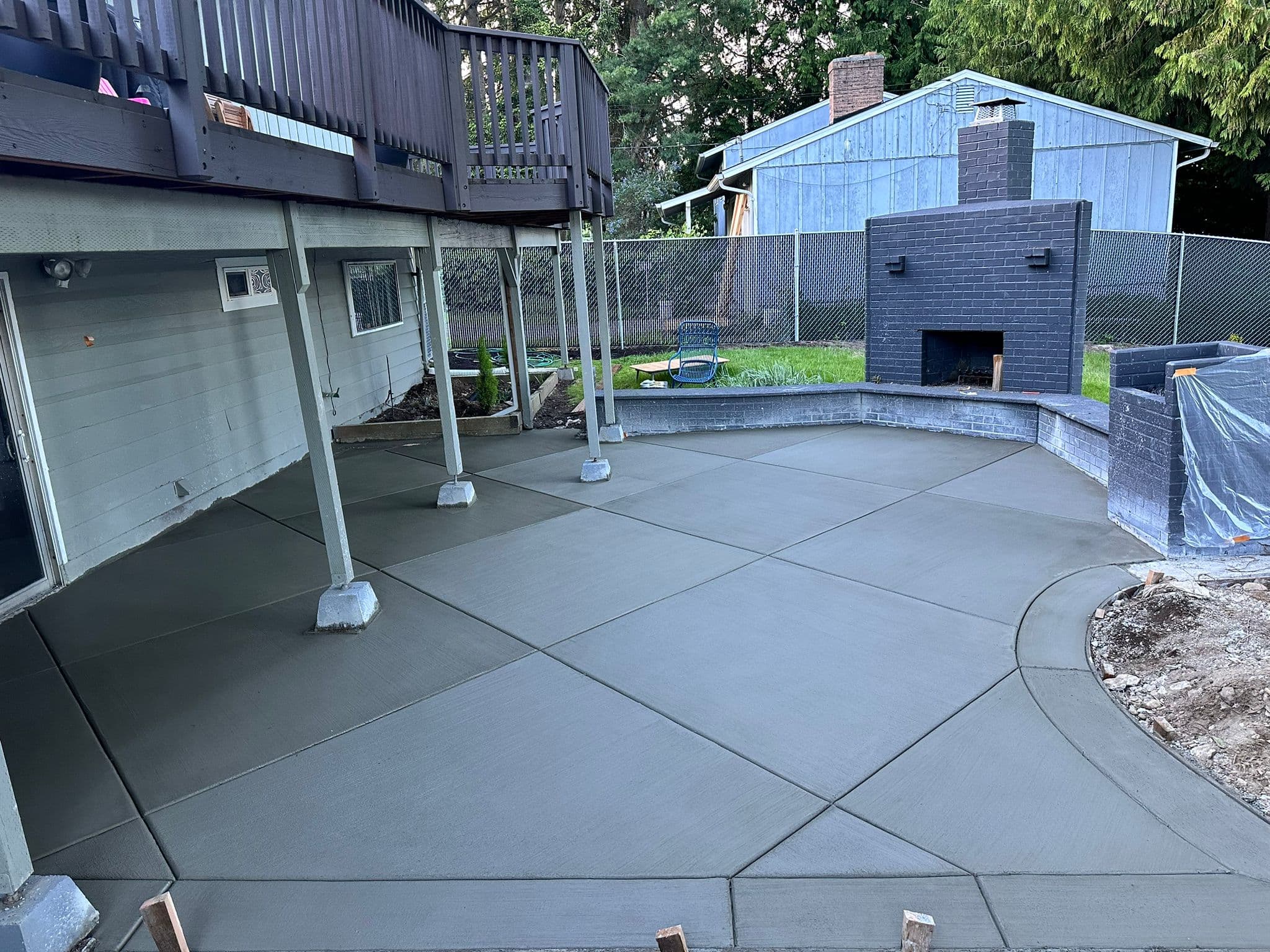 Concrete patio with curved edges and control joints beside an outdoor fireplace
