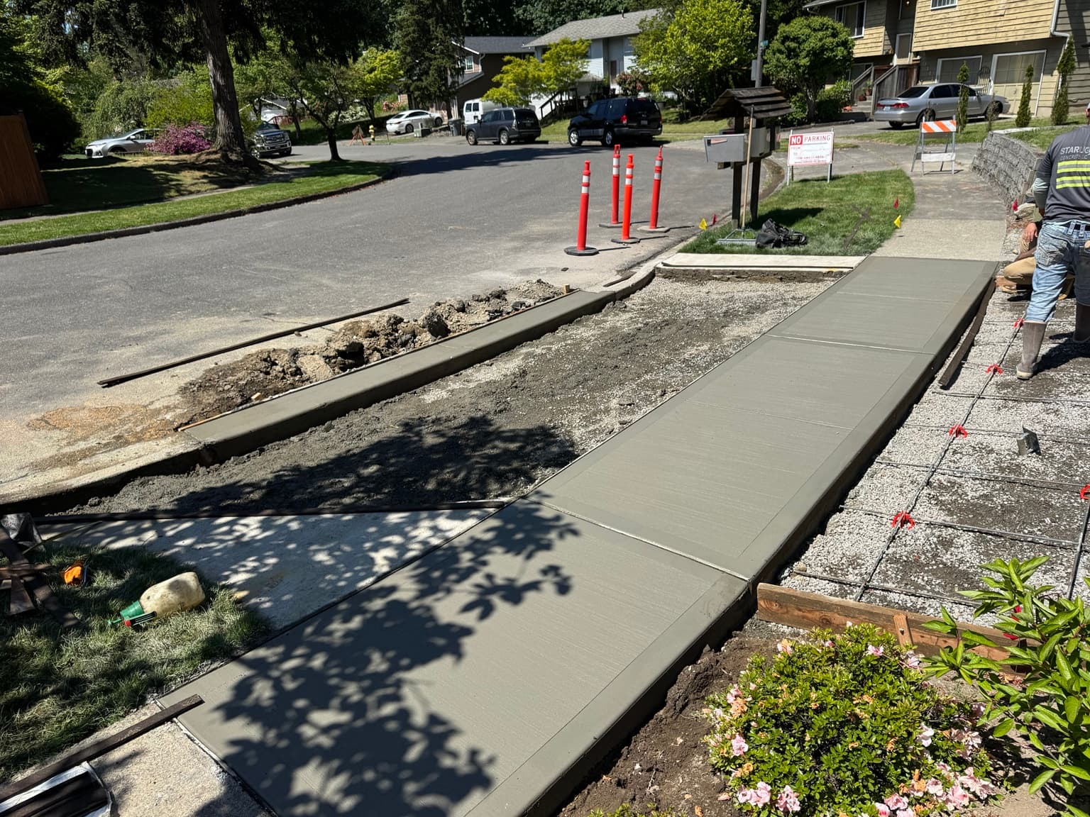 Freshly finished concrete sidewalk and curb alongside a residential street